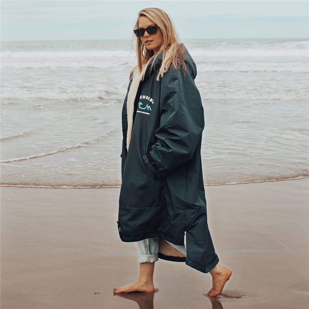 A woman wearing a long-sleeved Bleubird Nordic outdoor changing robe with a hood