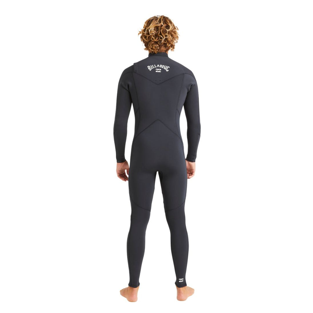 A man standing in a black long sleeve Billabong Absolute Natural 3/2mm mens wetsuit with a chest zip entry system. View of the back