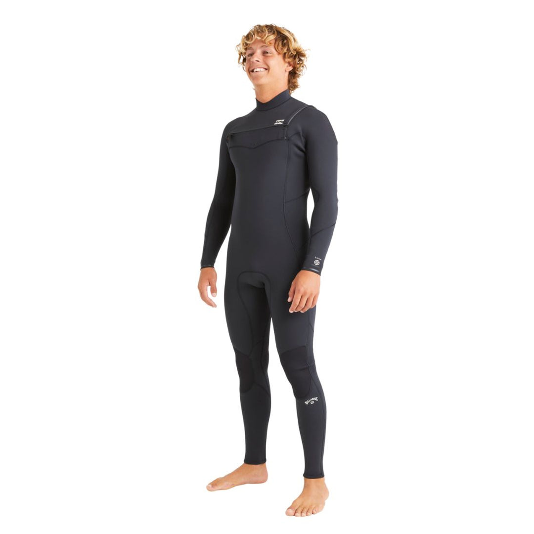 A man standing in a black long sleeve Billabong Absolute Natural 3/2mm mens wetsuit with a chest zip entry system.