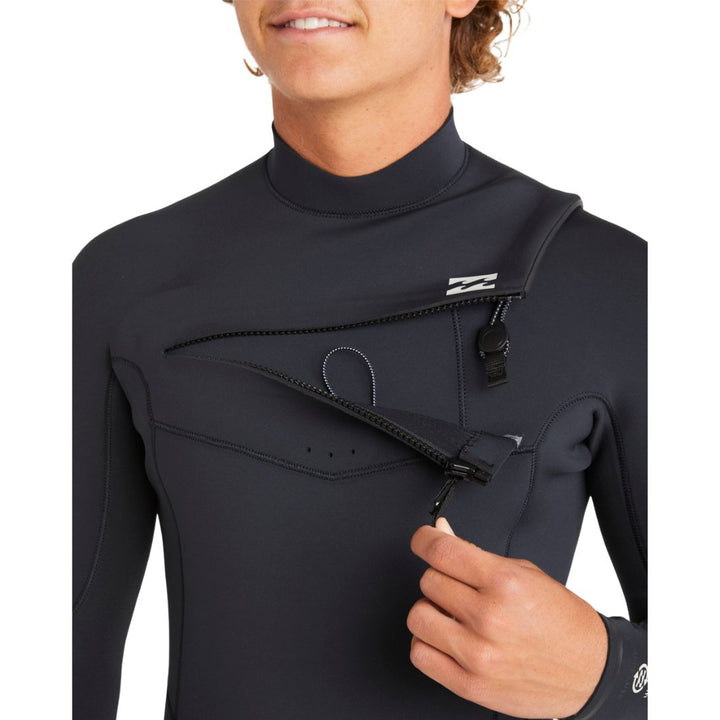 Close-up of a man wearing a Billabong Absolute Natural black mens wetsuit opening the chest zip entry.