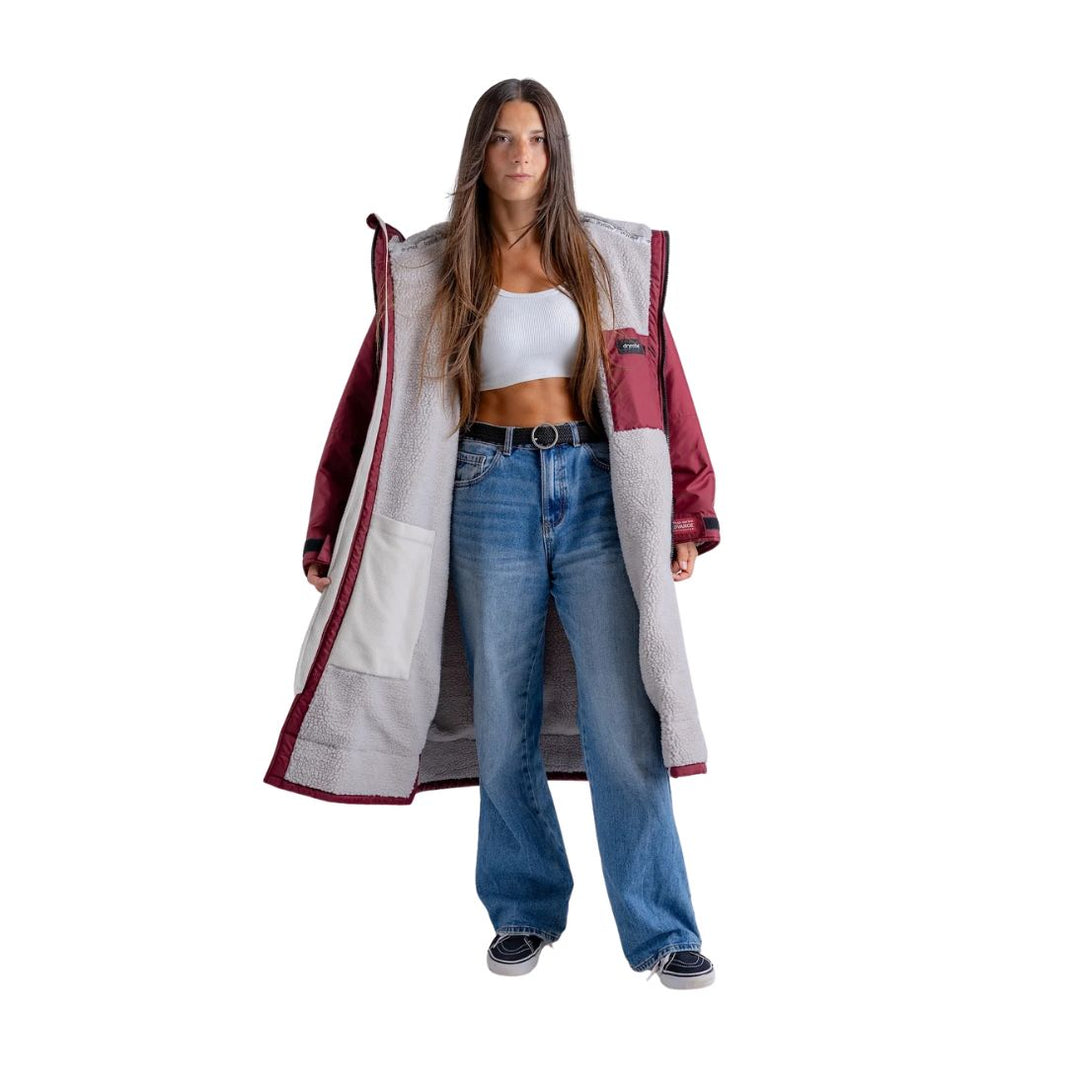 Woman wearing a long, patterned coat over a white top and blue jeans on a white background