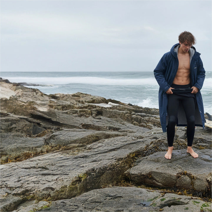 Surfer changing out of a wetsuit under a navy Gul Revorobe