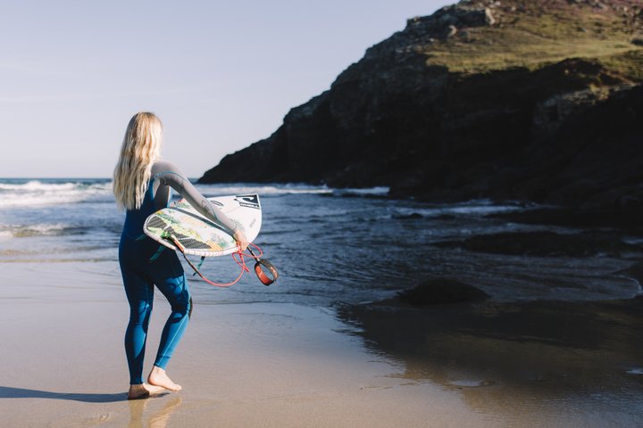 A model wearing a full-body O'Neill kids wetsuit about to go surfing 
