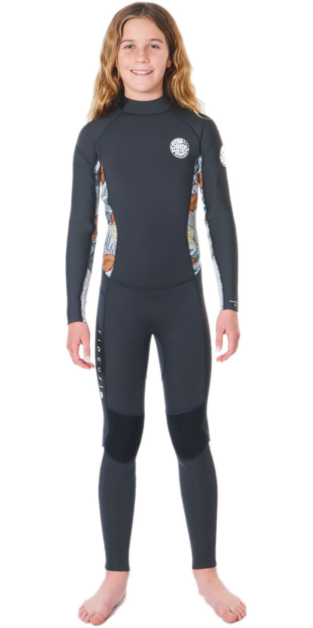 A girl wearing a black and multicolored floral Rip Curl Dawn Patrol 5mm kids wetsuit with a back zip.